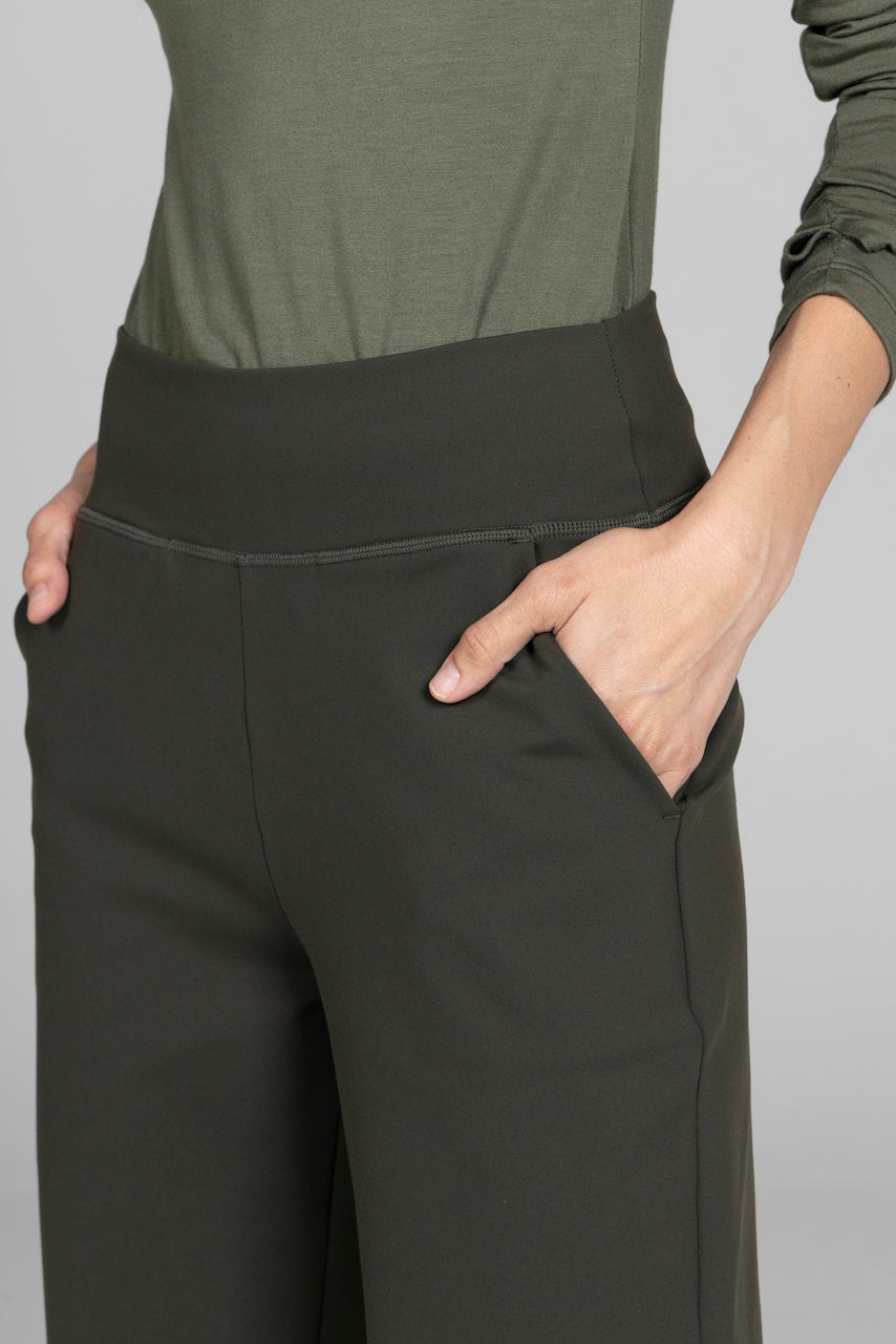 Person wearing dark green pants and a matching top against a gray background