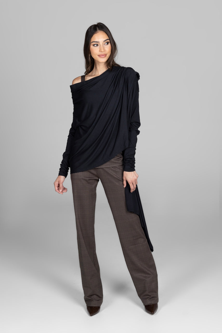 Woman wearing a black off-shoulder top and brown pants on a gray background