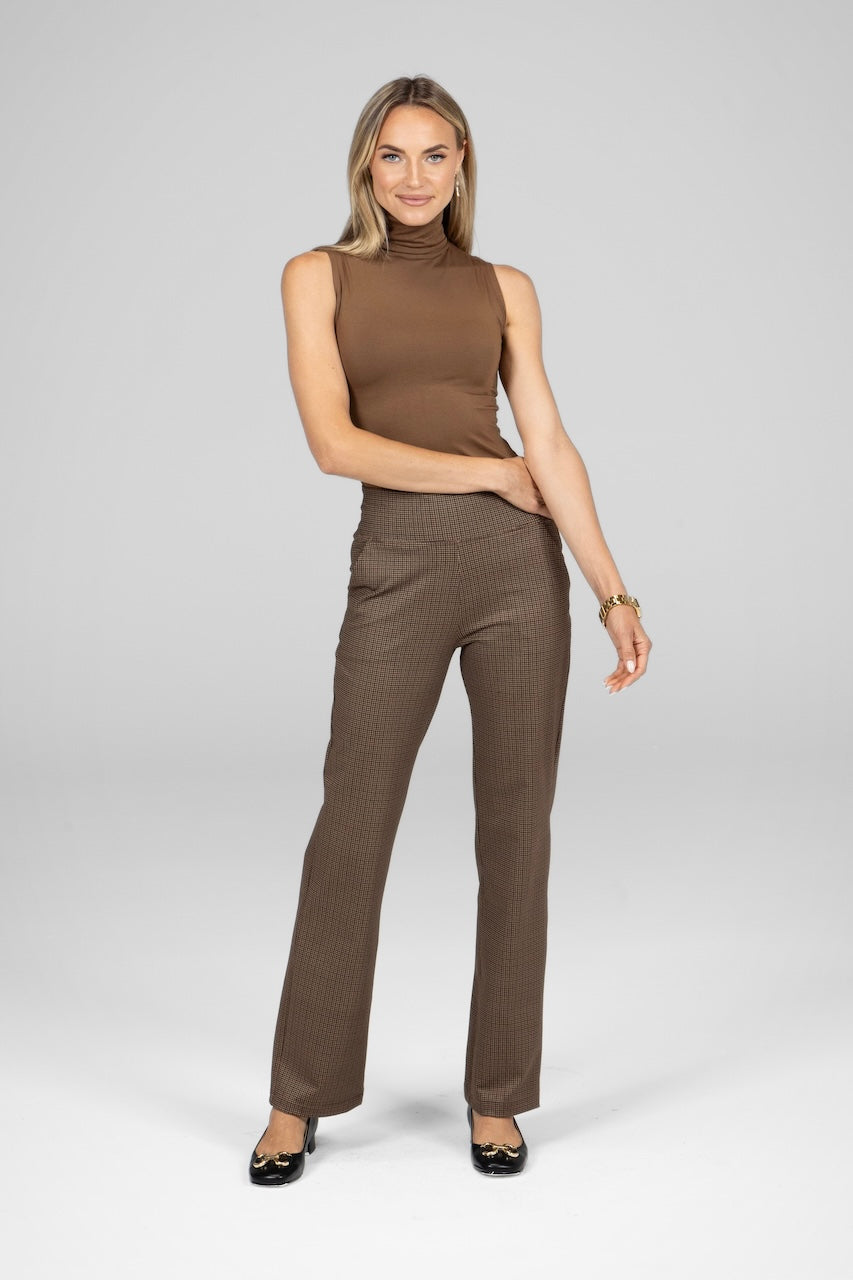 Woman wearing a brown sleeveless top and pants on a white background