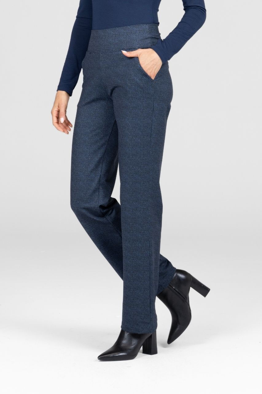 Person wearing a navy top and blue pants with black shoes on a white background