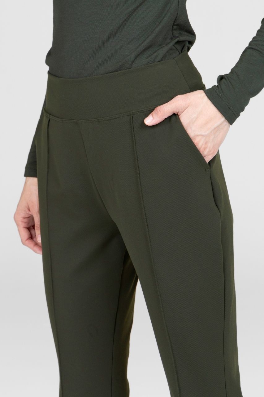 Person wearing olive green pants with a plain background