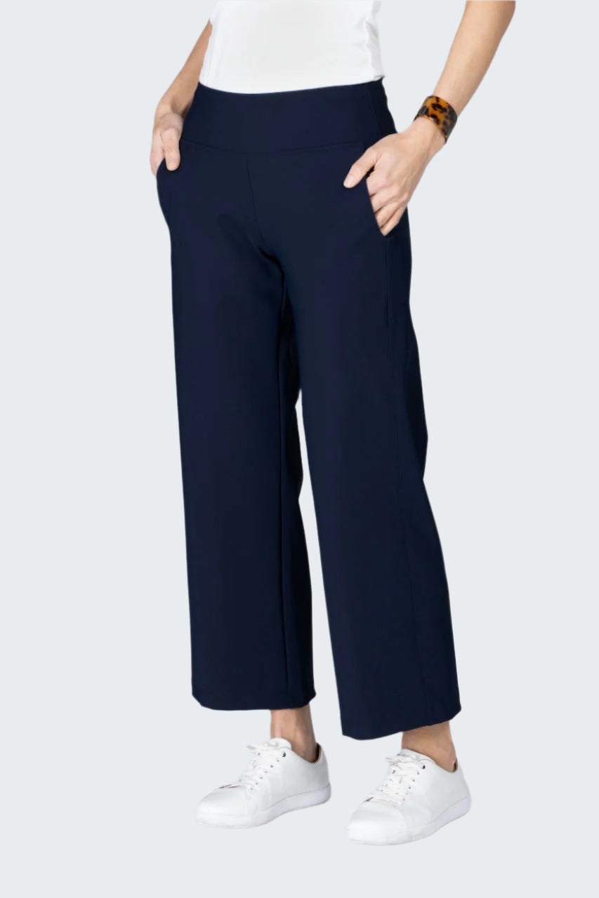 Person wearing navy wide-leg pants and white sneakers on a light gray background