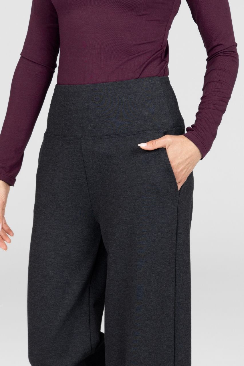 Person wearing a maroon long-sleeve top and dark gray wide-leg pants on a white background