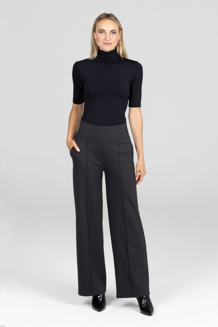 Woman wearing a black turtleneck and gray wide-leg pants on a white background