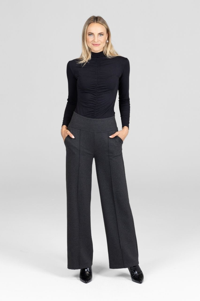 Woman wearing a black turtleneck and gray wide-leg pants on a white background