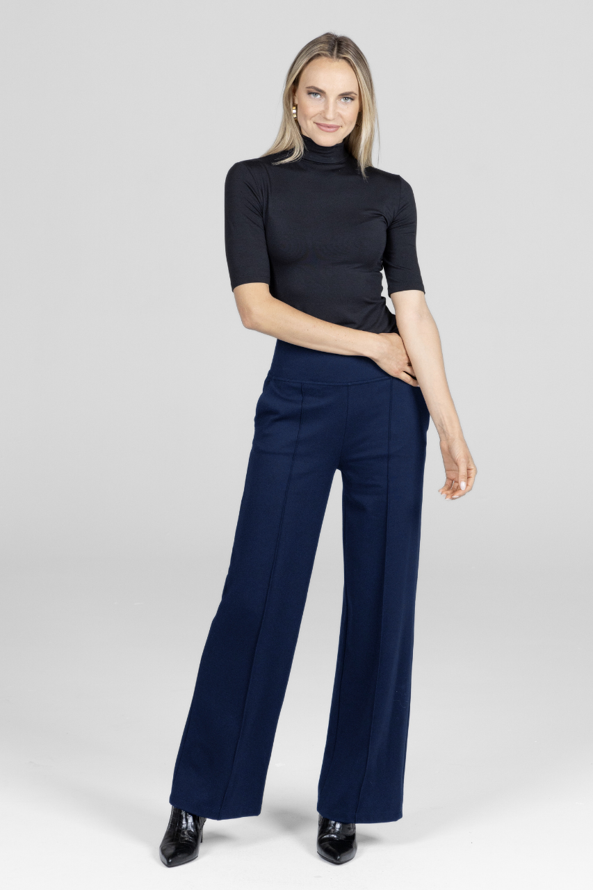 Woman wearing a black turtleneck and navy wide-leg pants on a white background
