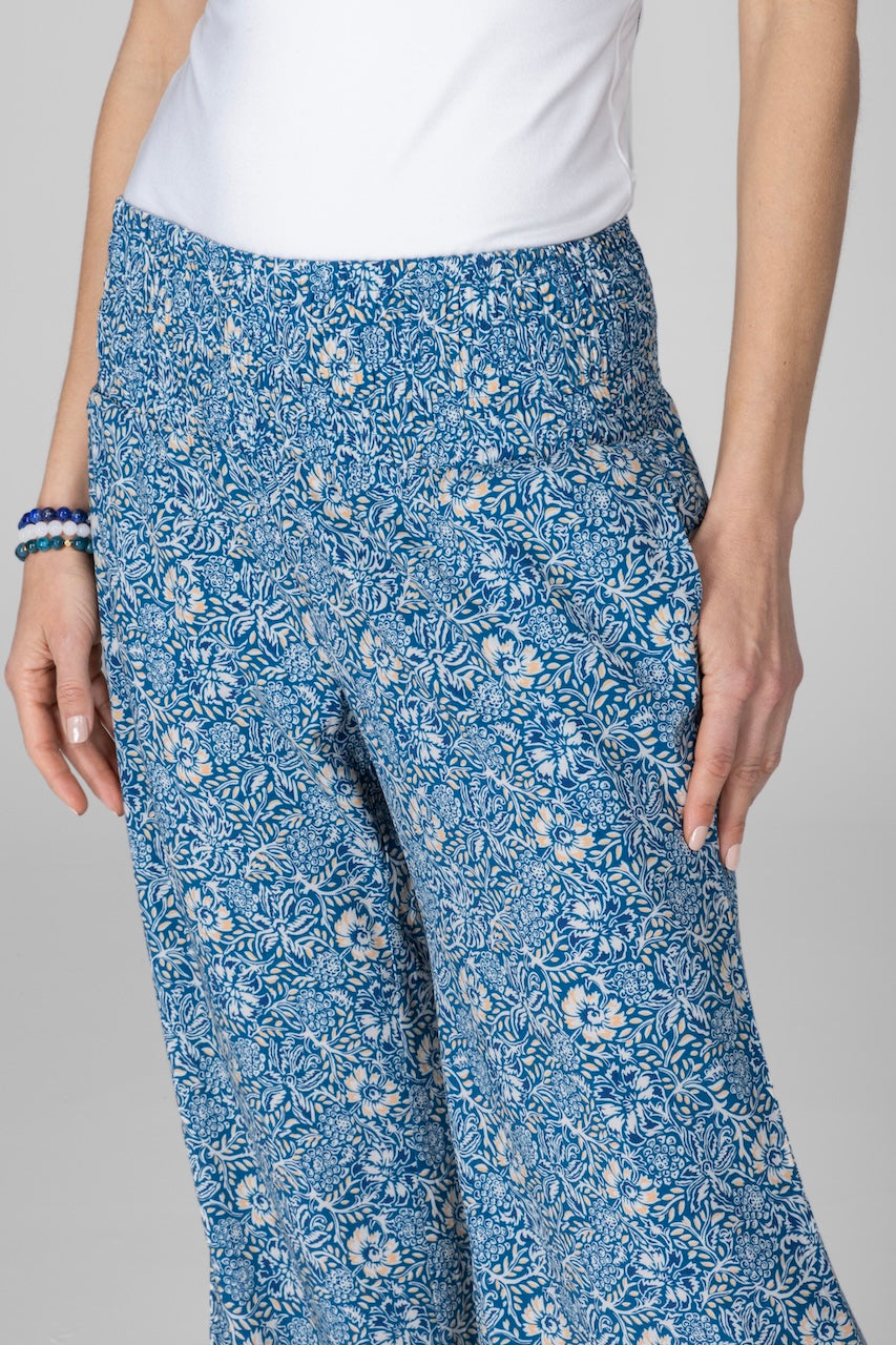 Blue floral-patterned pants worn by a person on a gray background
