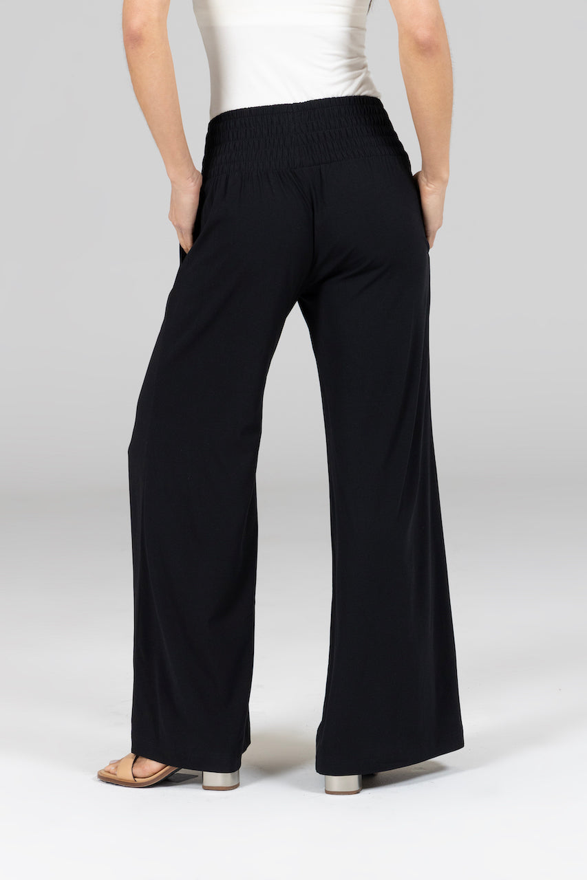 Person wearing black wide-leg pants on a plain background