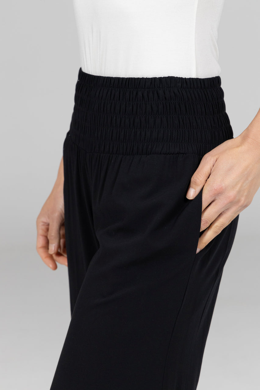 Black pants worn with a white top on a light gray background