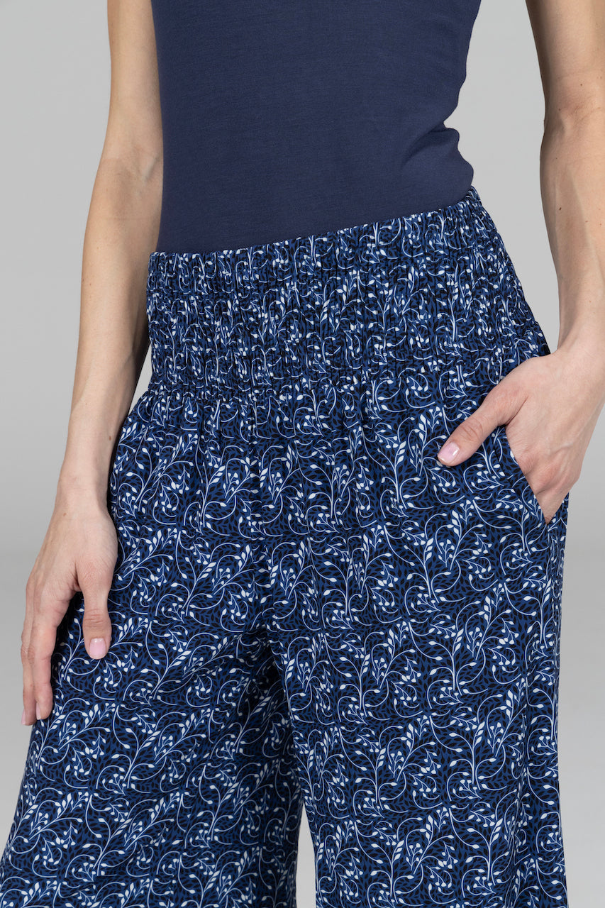 Navy blue floral-patterned pants worn by a person on a gray background