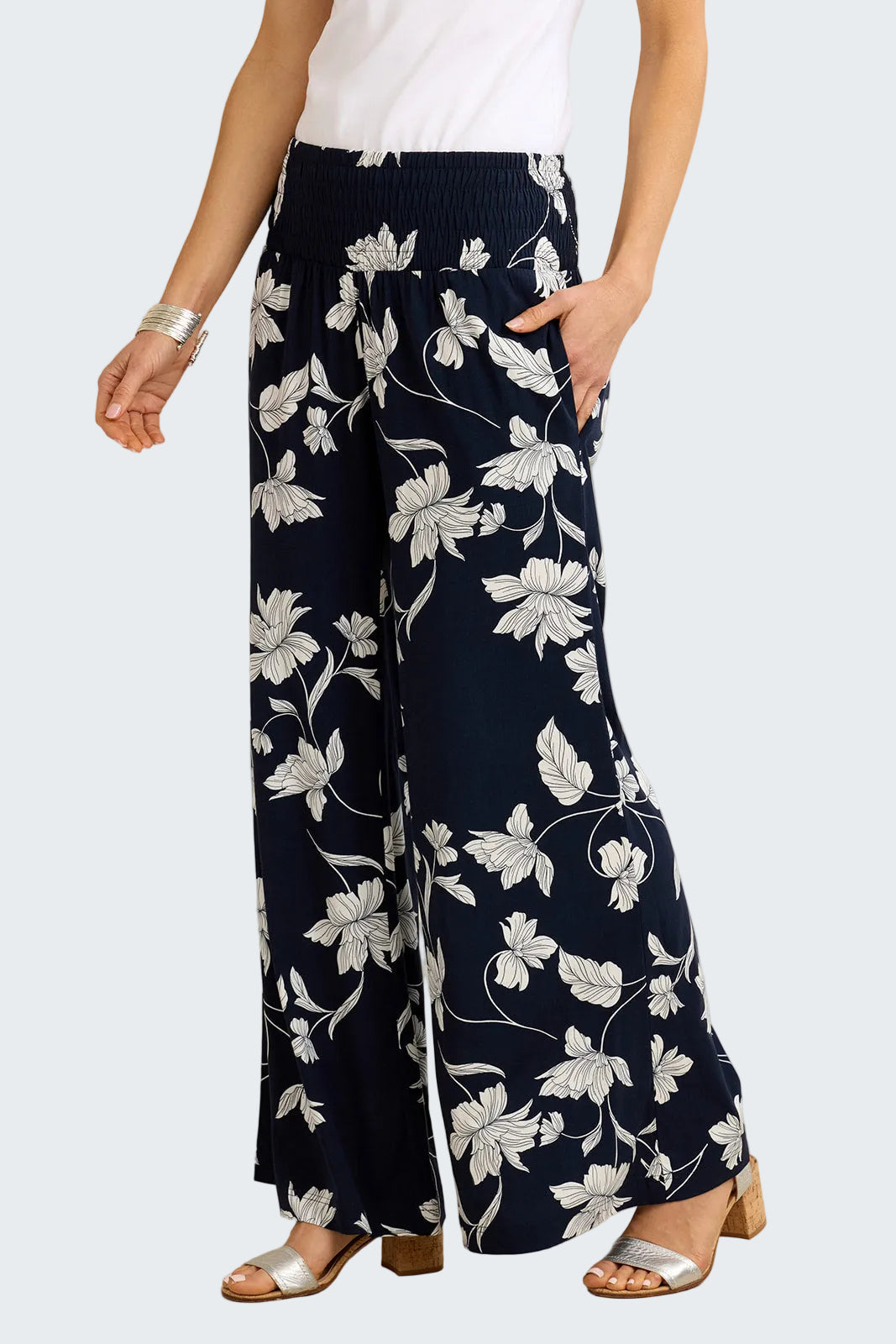 Navy blue pants with white floral pattern worn by a person on a beige background