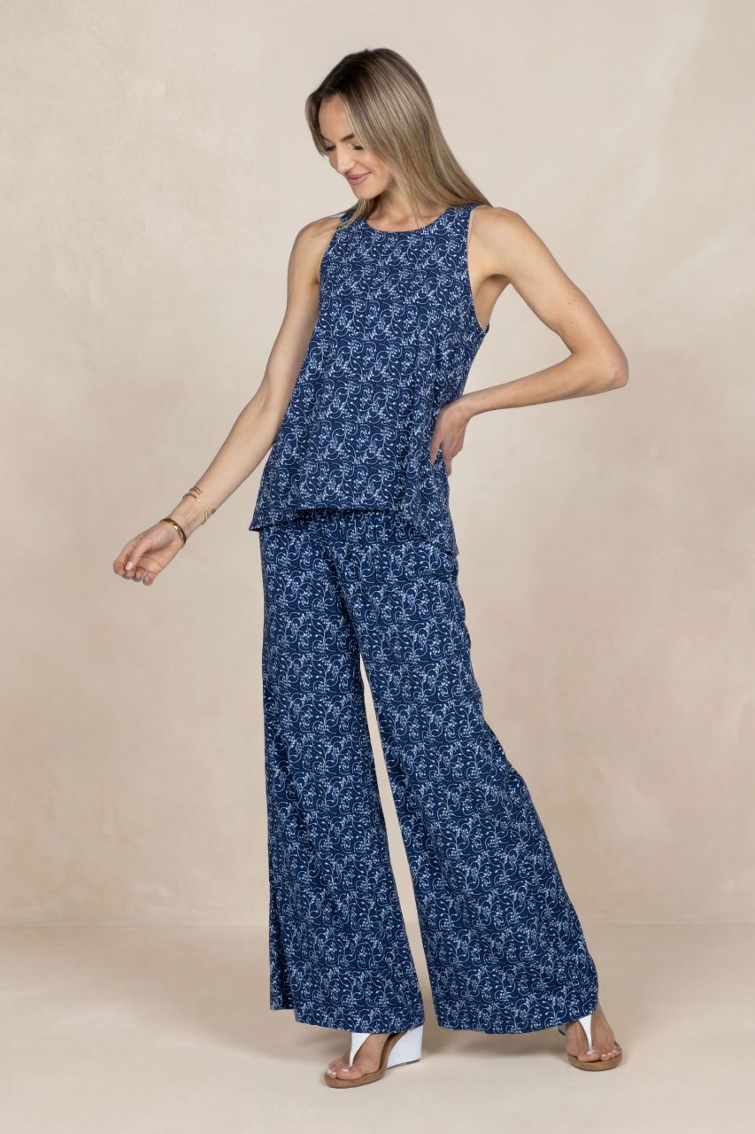 Woman wearing a blue floral sleeveless top and wide-leg pants on a beige background