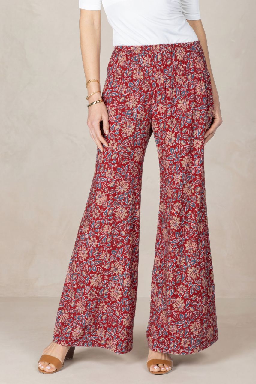 Red floral-patterned pants worn by a person on a beige background