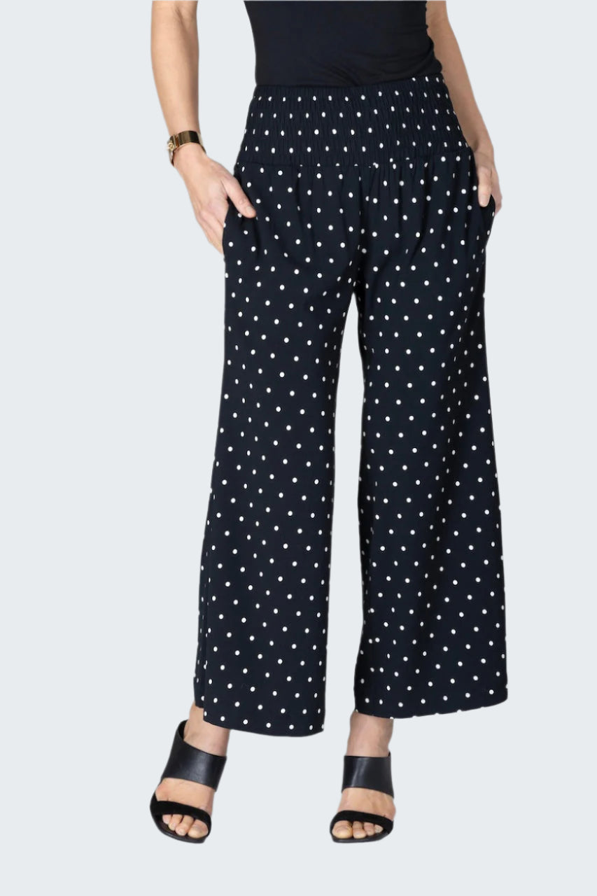 Black pants with white polka dot pattern worn by a person on a light gray background