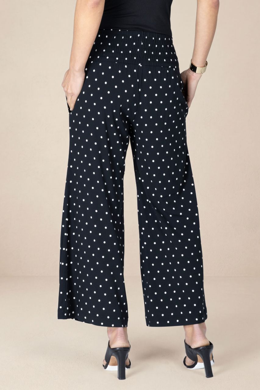 Black pants with white star pattern worn by a person on a beige background