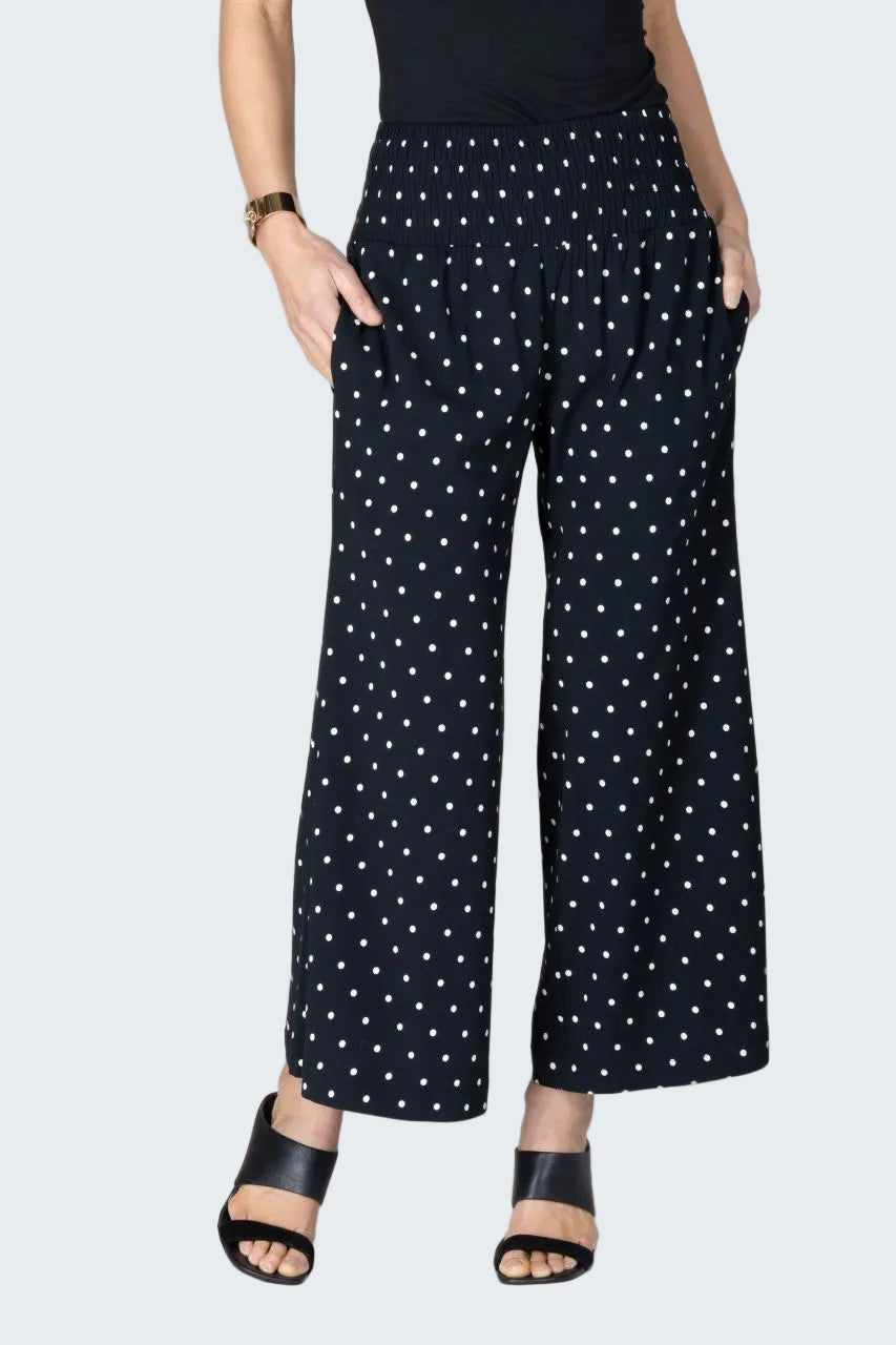 Person wearing black polka dot pants on a beige background