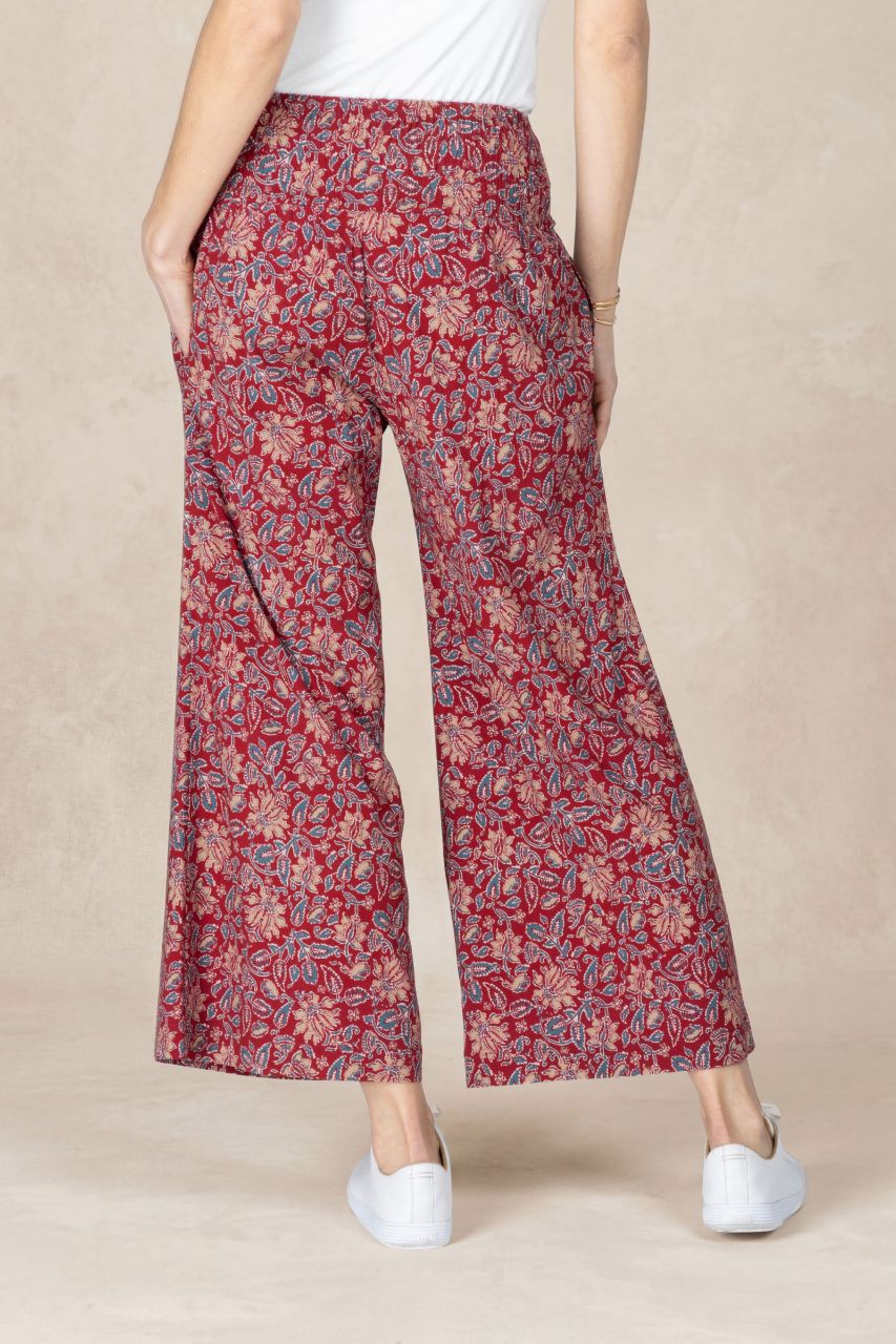 Red floral-patterned pants worn by a person on a beige background