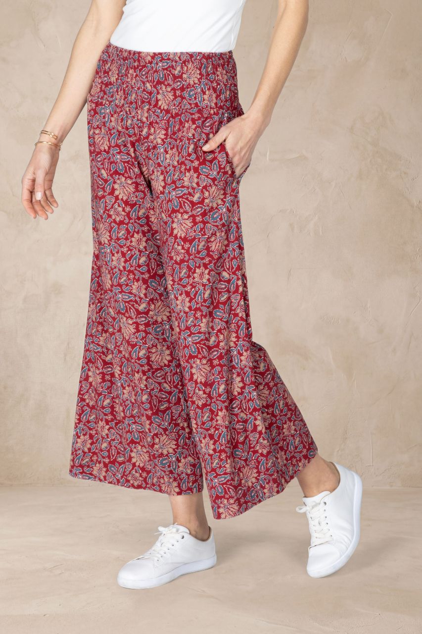 Person wearing red floral wide-leg pants with a beige background