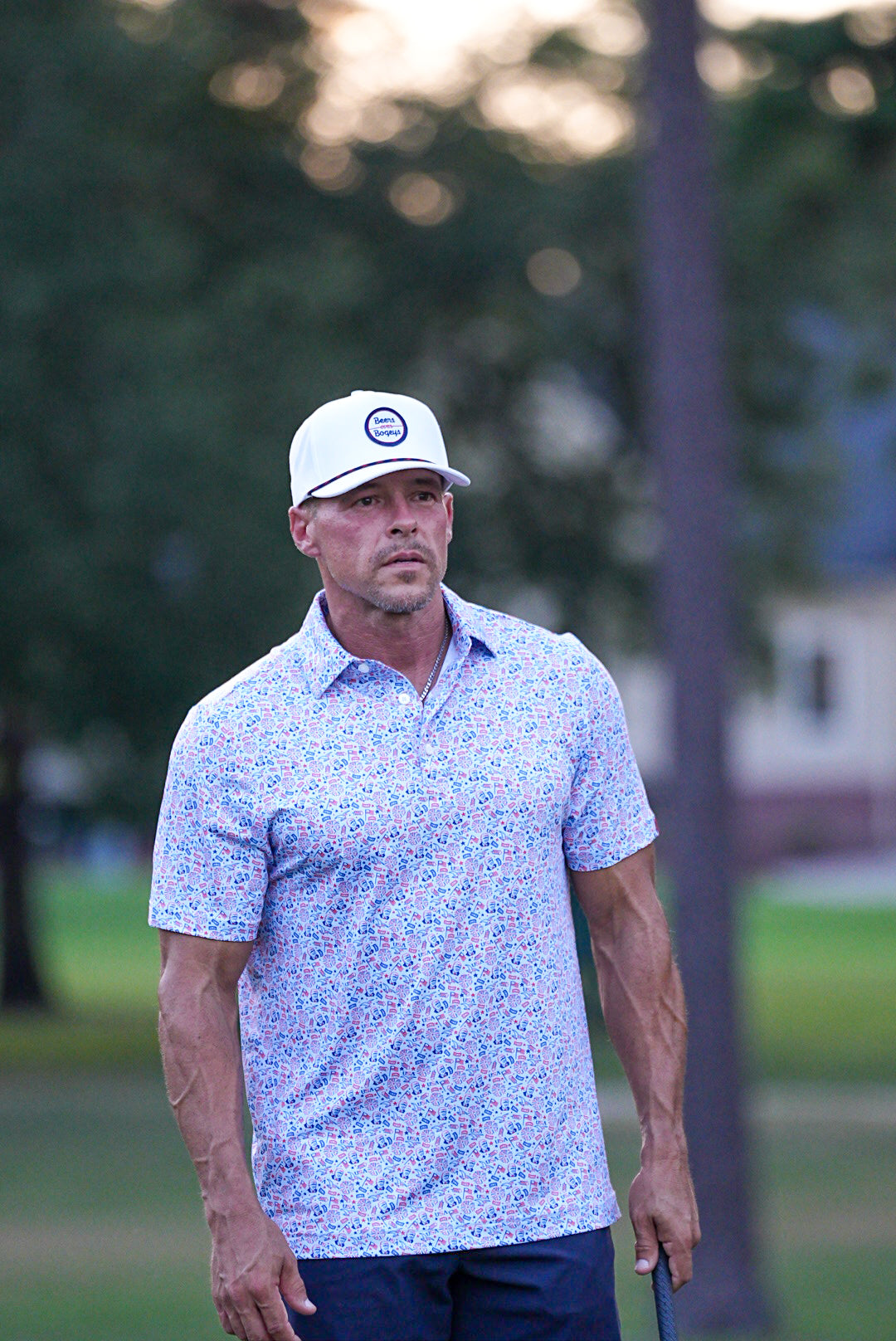 Man wearing a white cap and patterned shirt on a golf course
