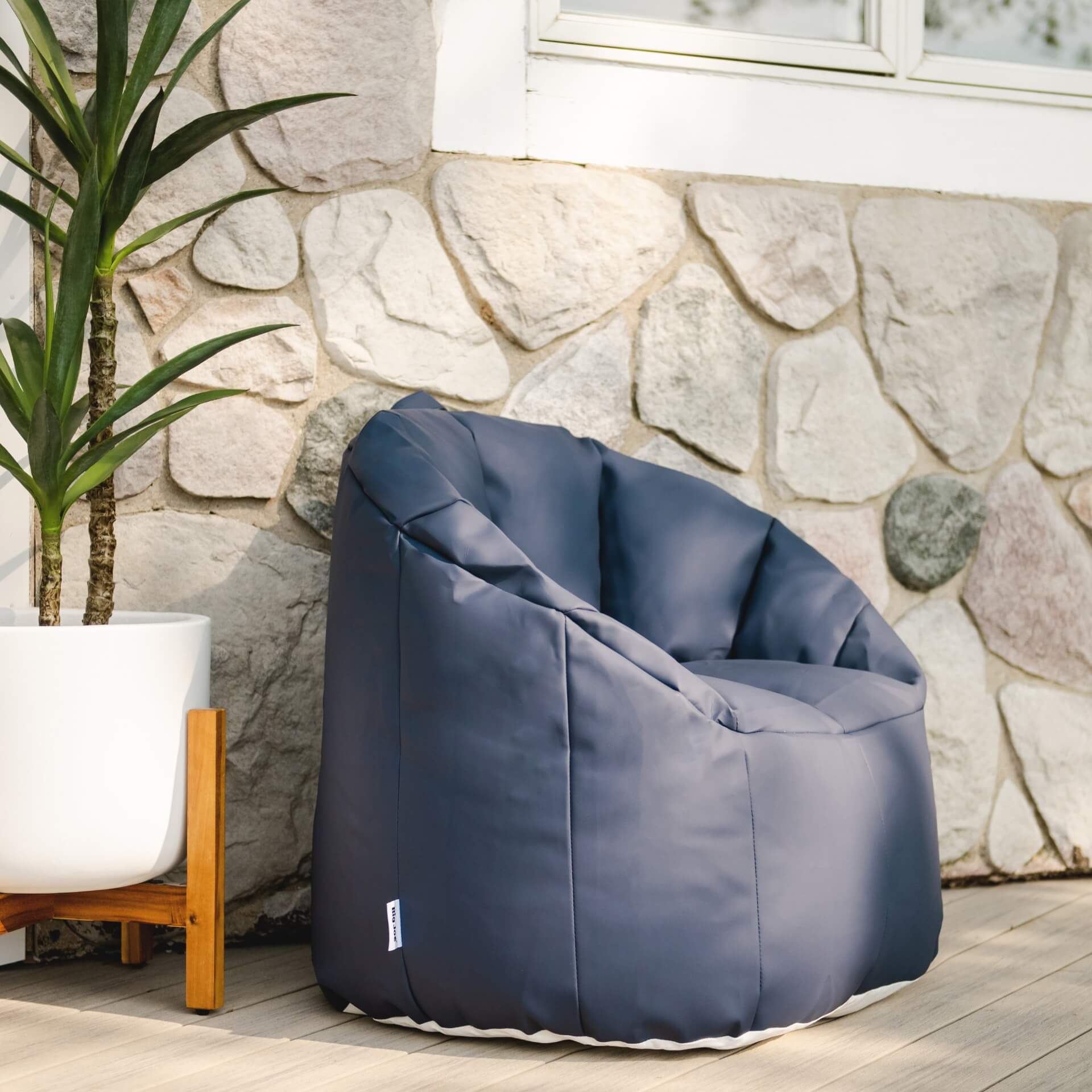 Blue bean bag chair against a stone wall with a plant in the background