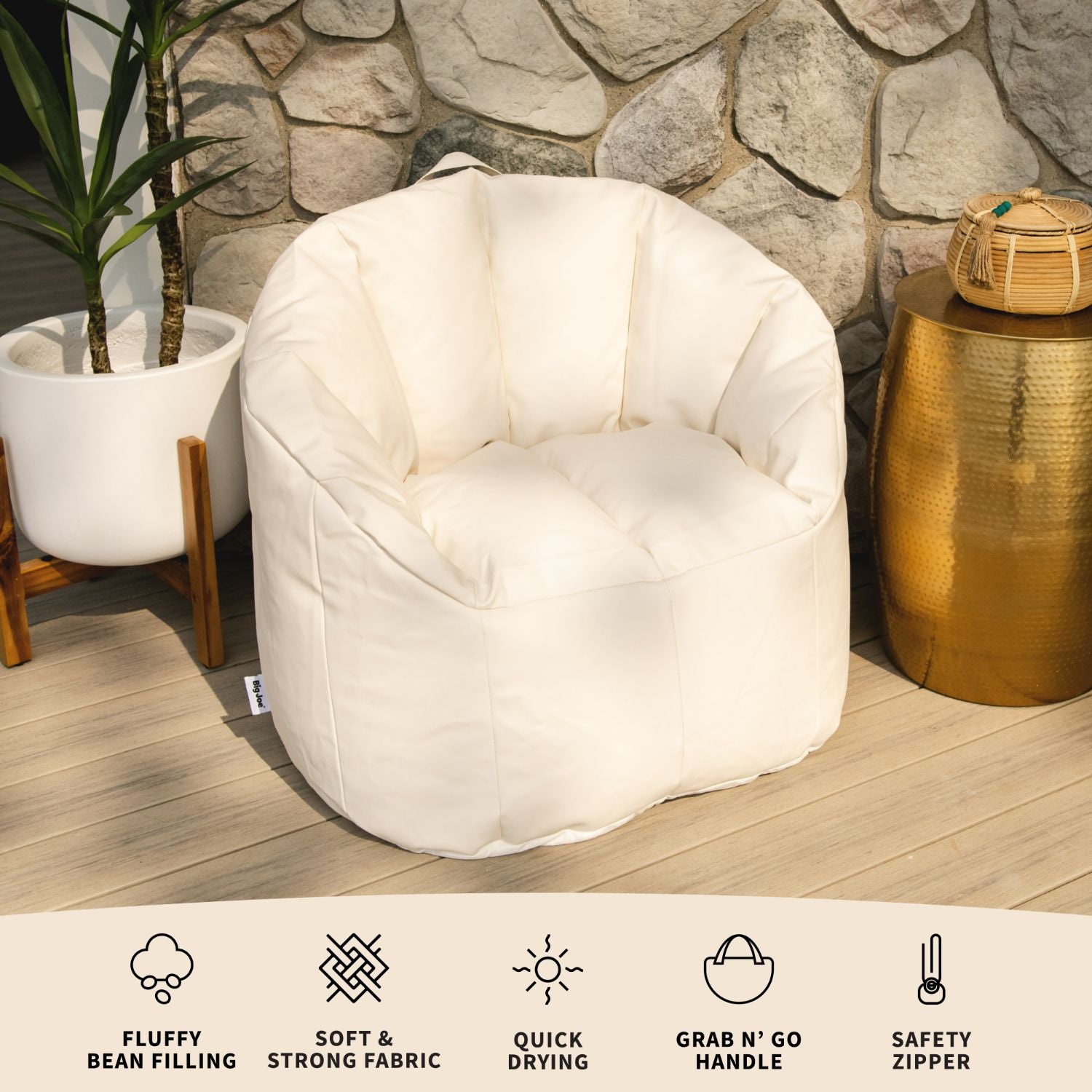 White bean bag chair in a room with a stone wall and gold side table.