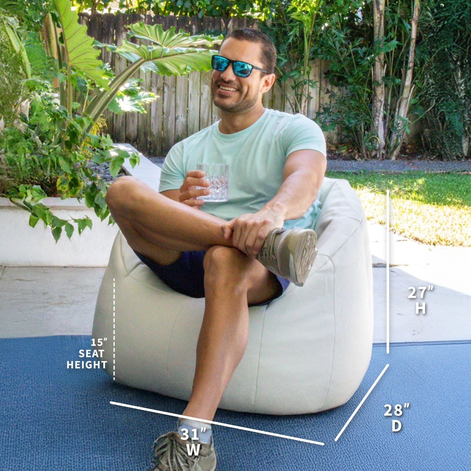 Man sitting on a white bean bag chair outdoors with measurements displayed.