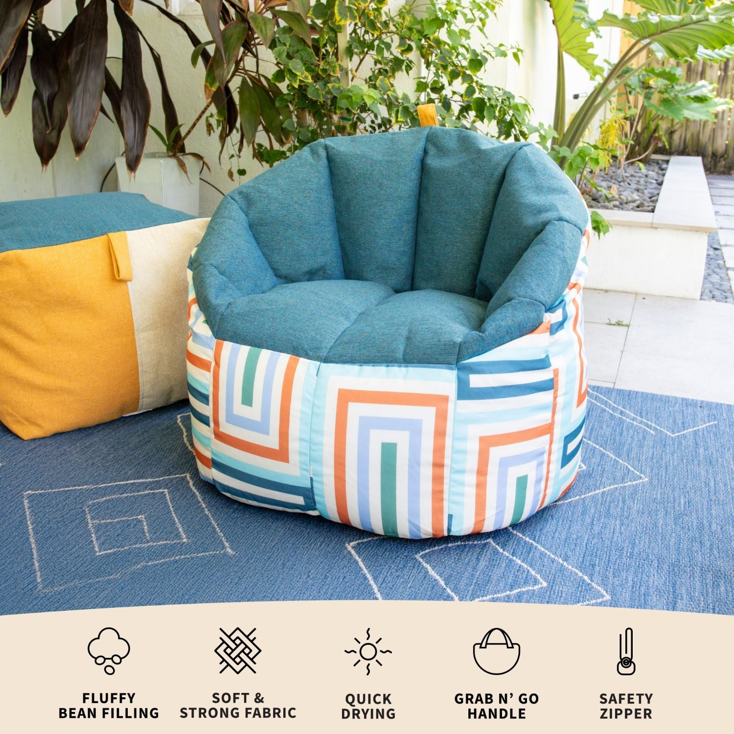 Colorful bean bag chair with geometric pattern on a blue rug outdoors.