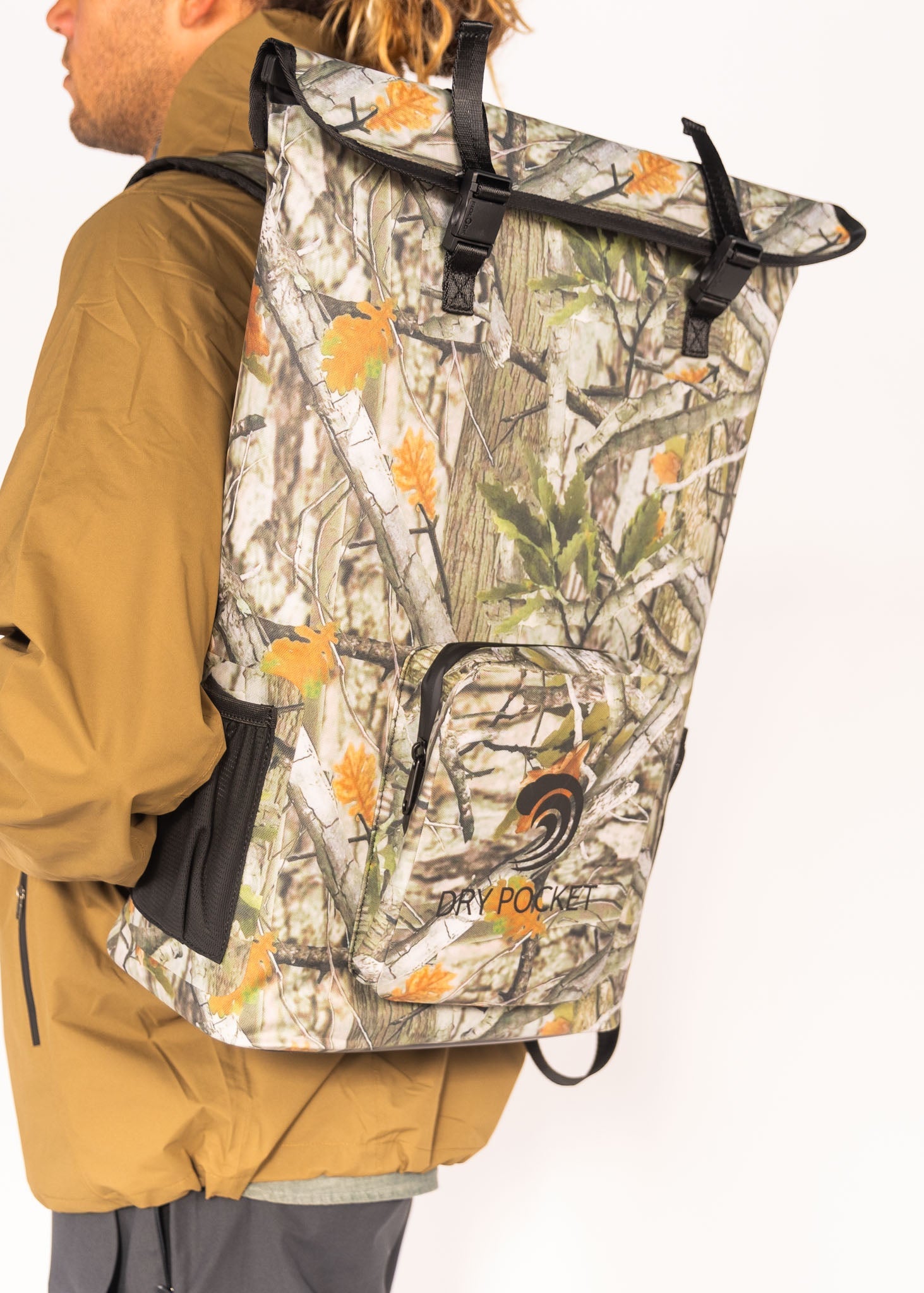 Person wearing a camouflage backpack with 'Dry Pak' branding on a white background