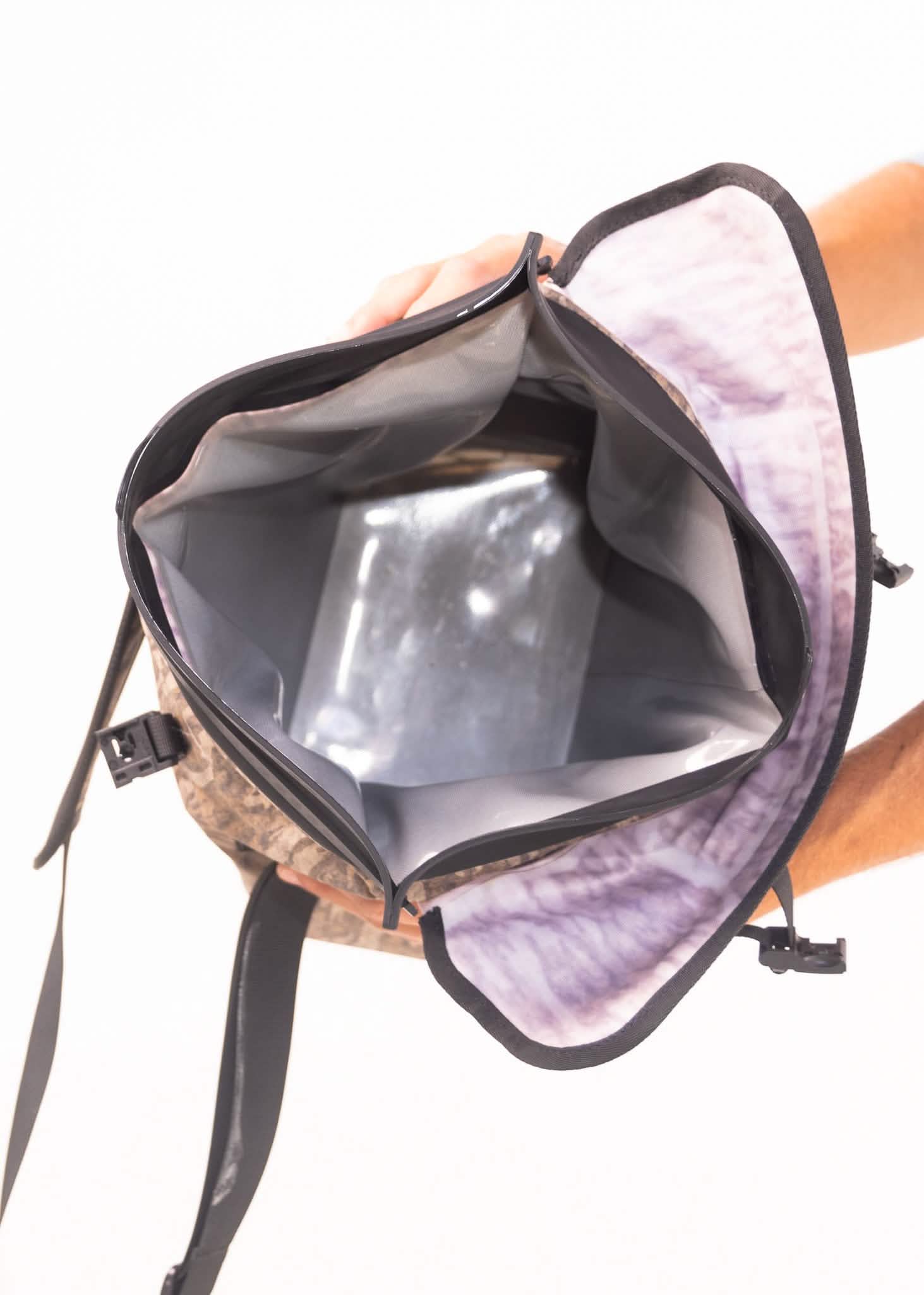 Backpack with a clear front pocket showing a metallic object inside, held by a person.