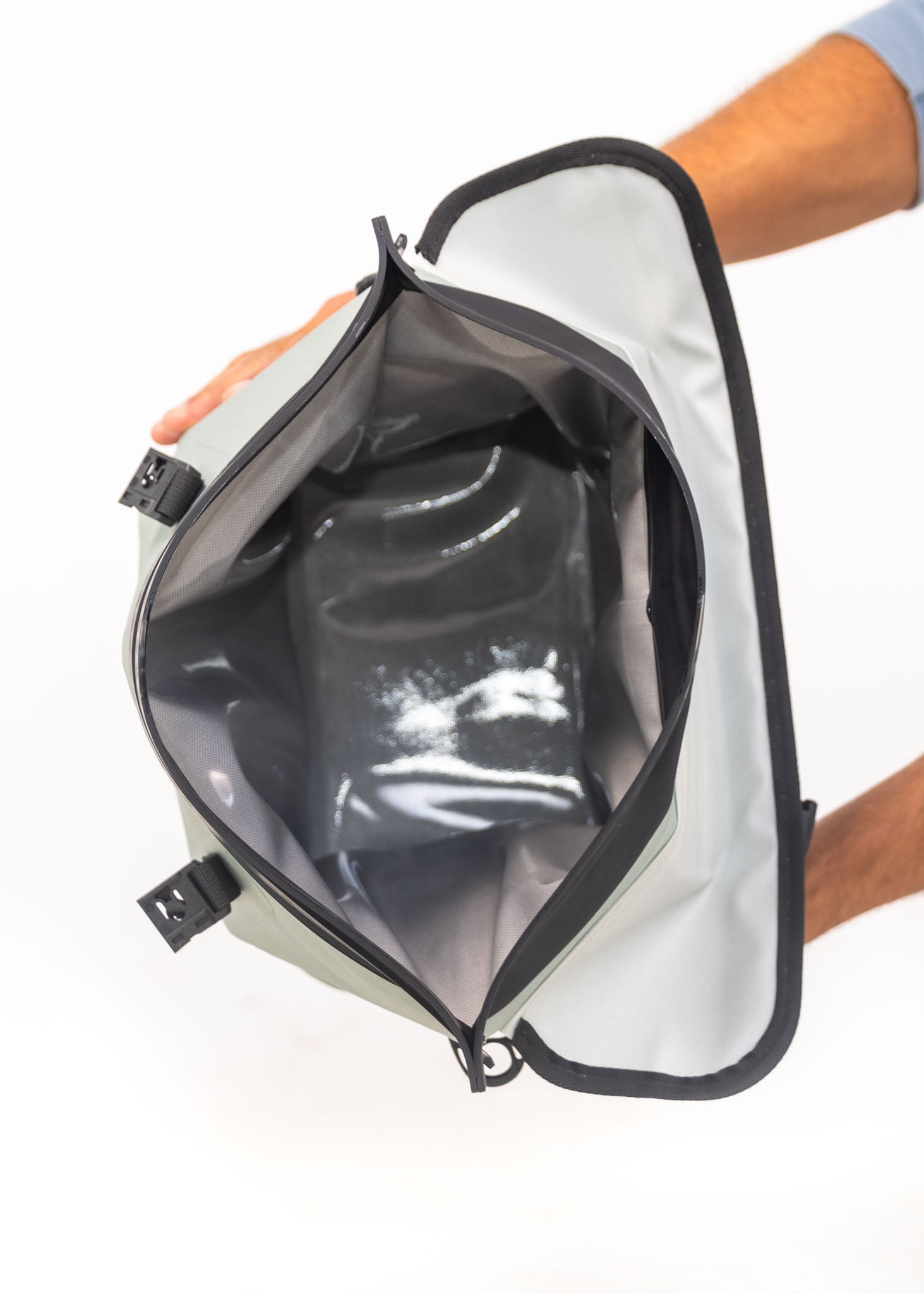 Person holding a transparent bag inside a larger container with a white background