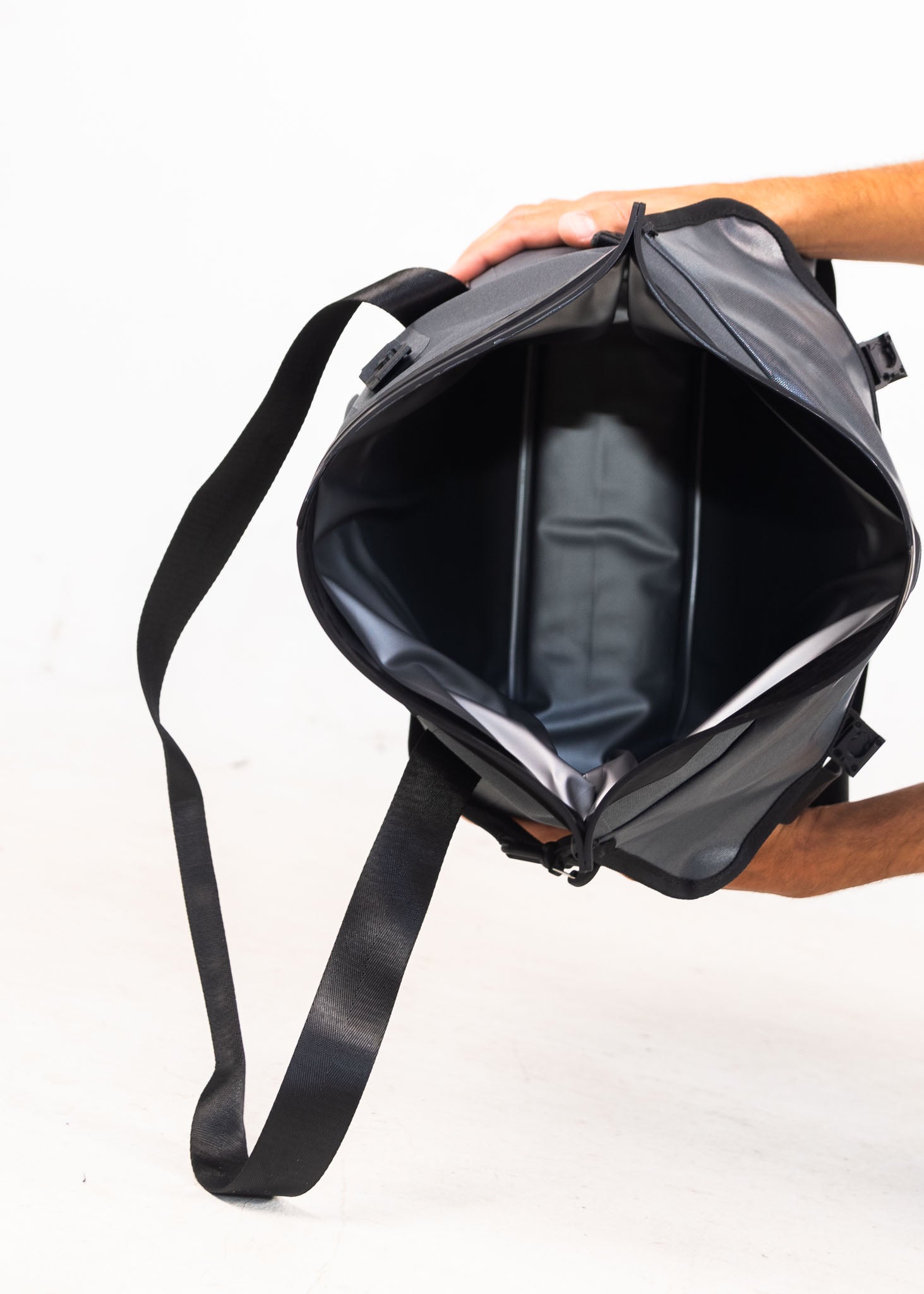 Person holding a black backpack with a white background