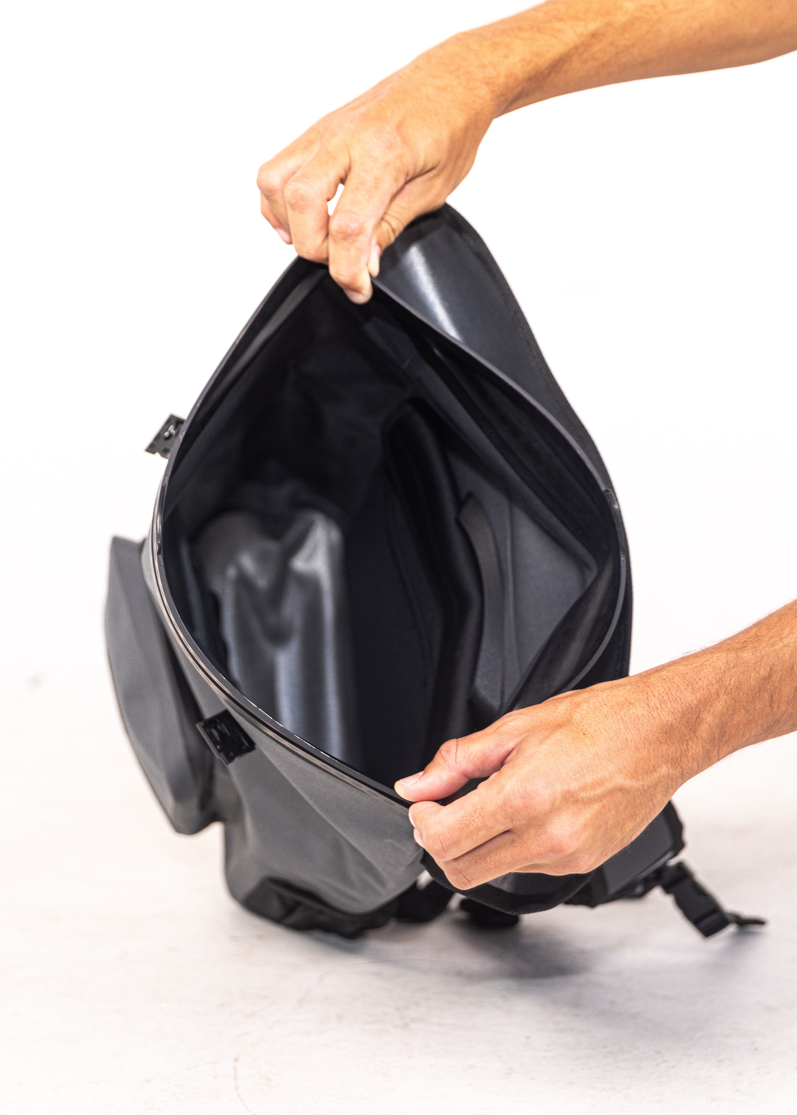 Person opening a black backpack on a white background