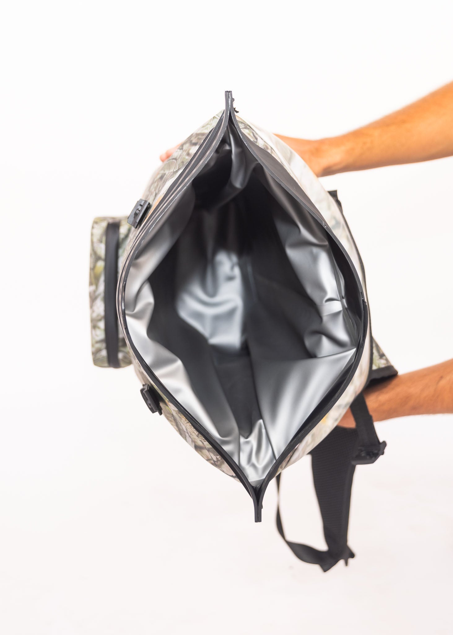 Person holding a camouflage backpack with a clear front pocket on a white background