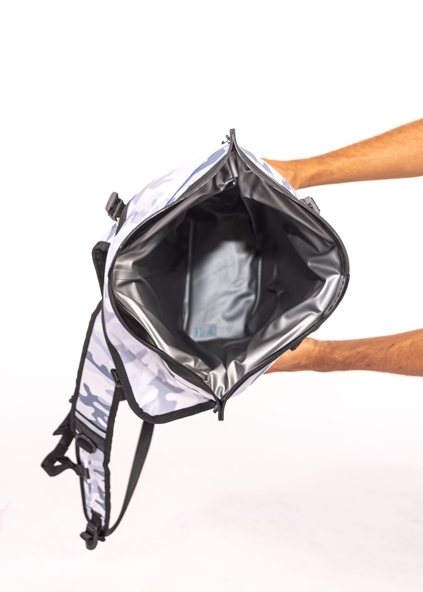 Person holding a white backpack with black straps on a white background