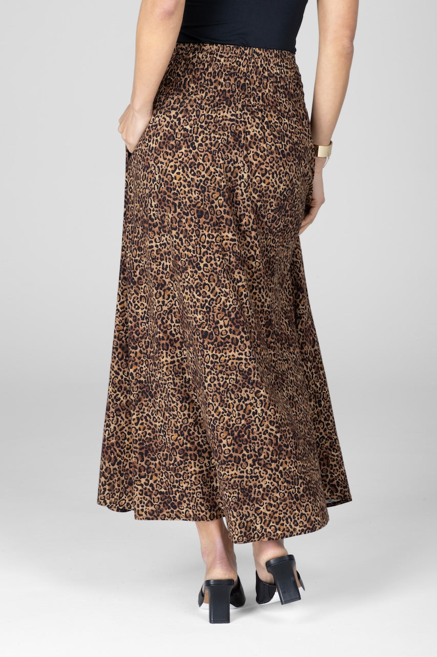 Person wearing a leopard print skirt on a plain background