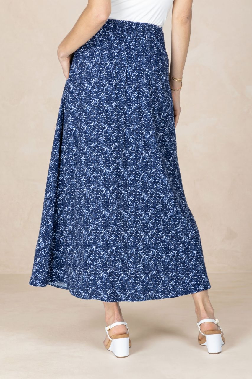 Person wearing a blue floral skirt on a beige background