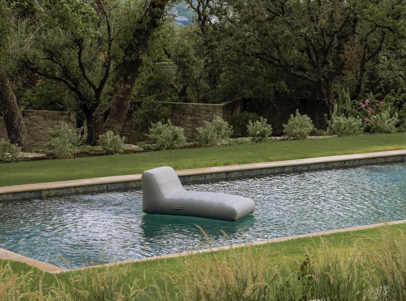 Modern outdoor chair by a pool with greenery in the background