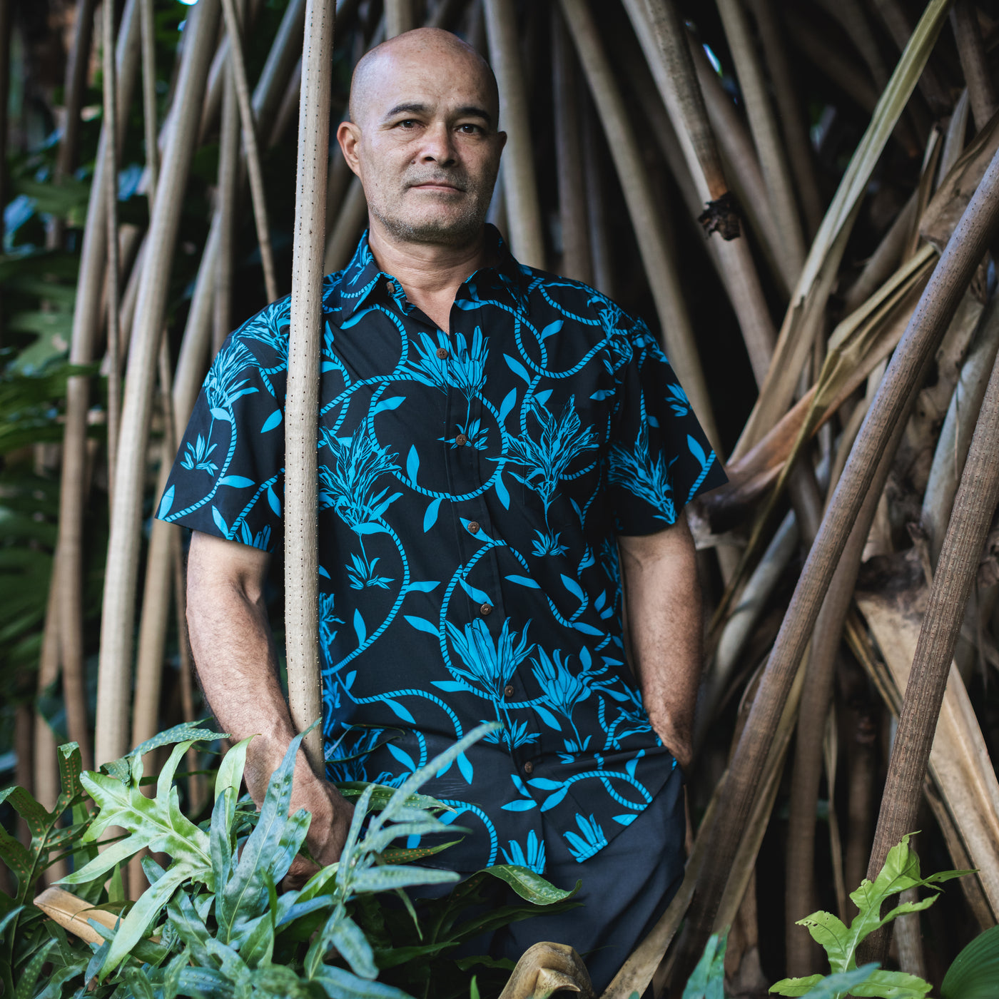 Man holding plants in front of a natural, leafy background