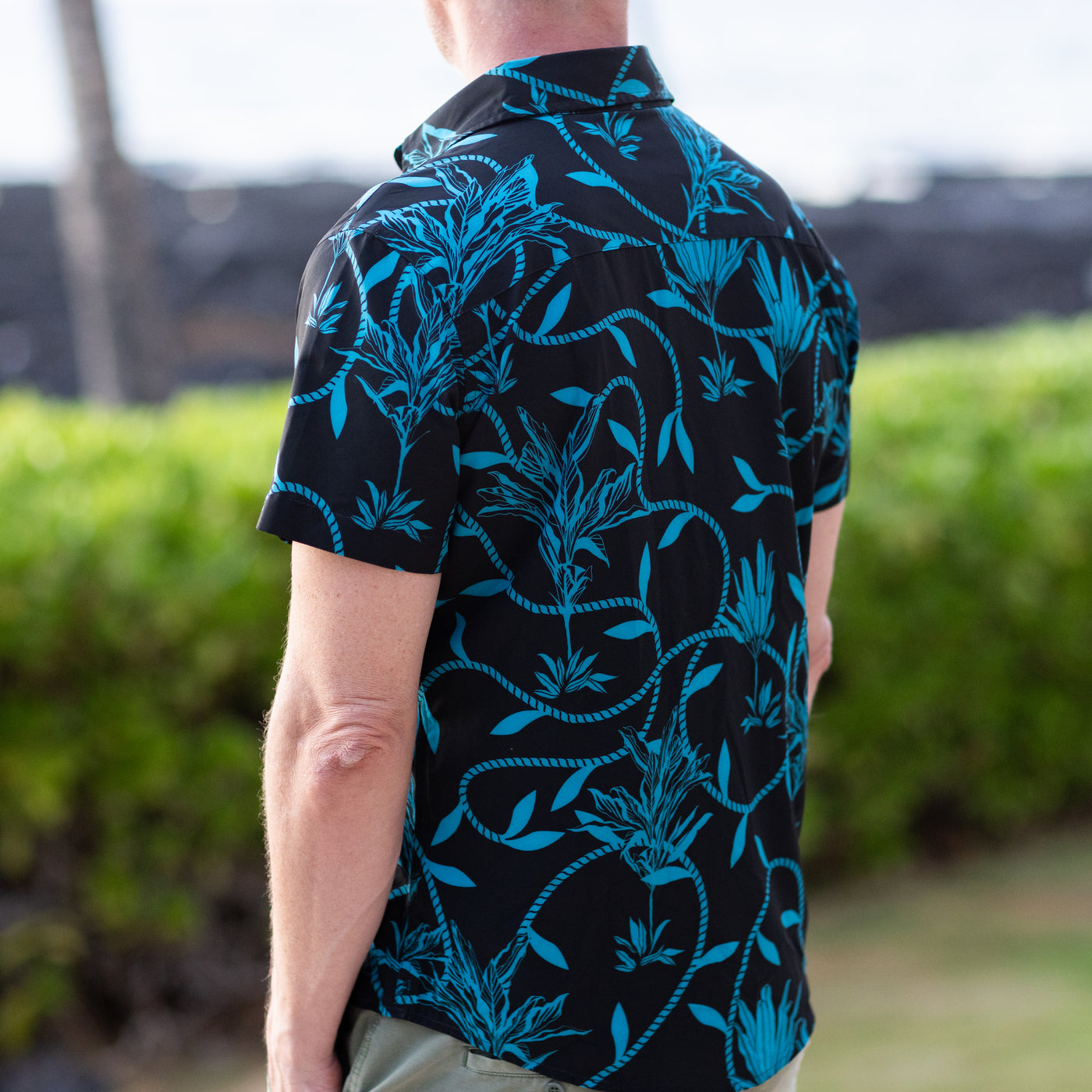 Person wearing a black shirt with blue floral pattern outdoors