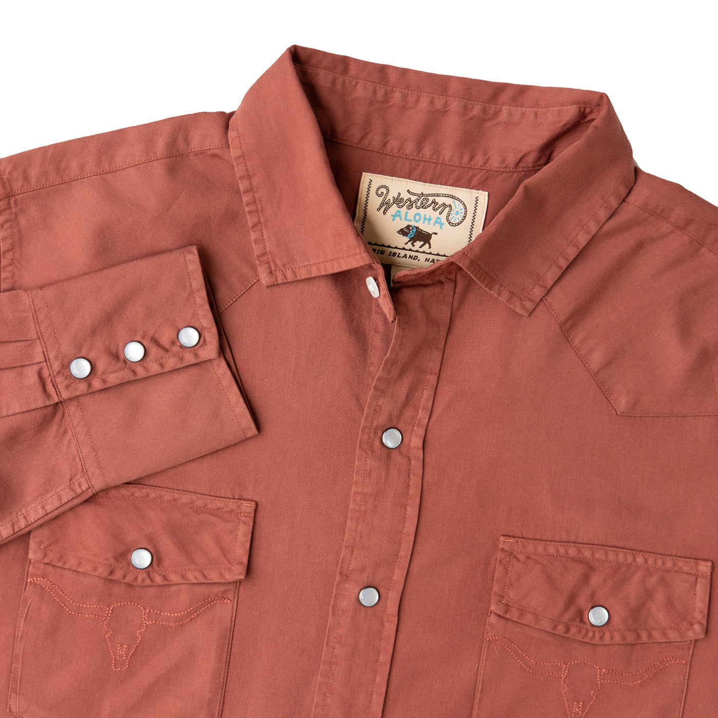 Close-up of a brown shirt with a brand label on a white background