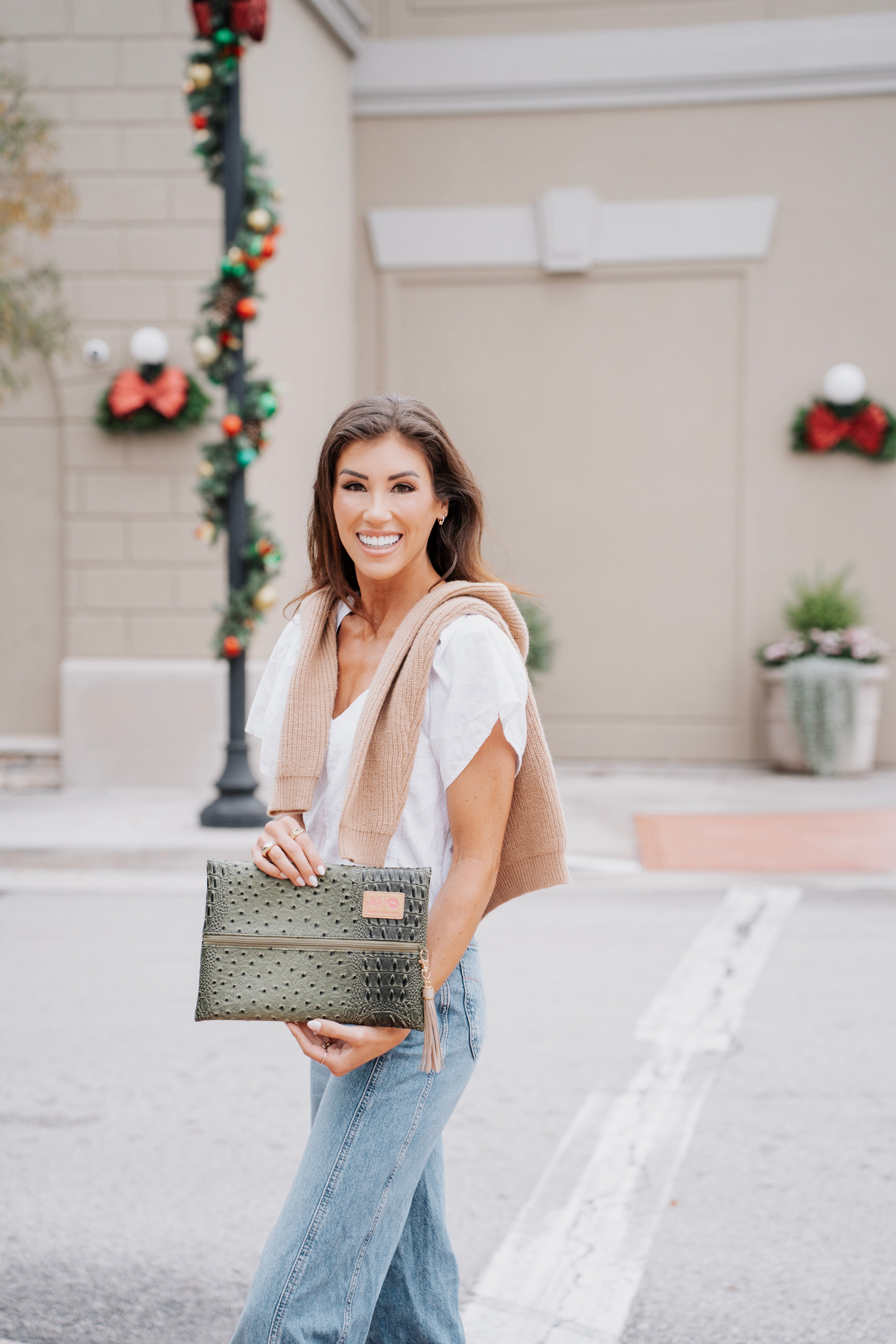Woman holding a clutch in an urban setting with decorative elements.