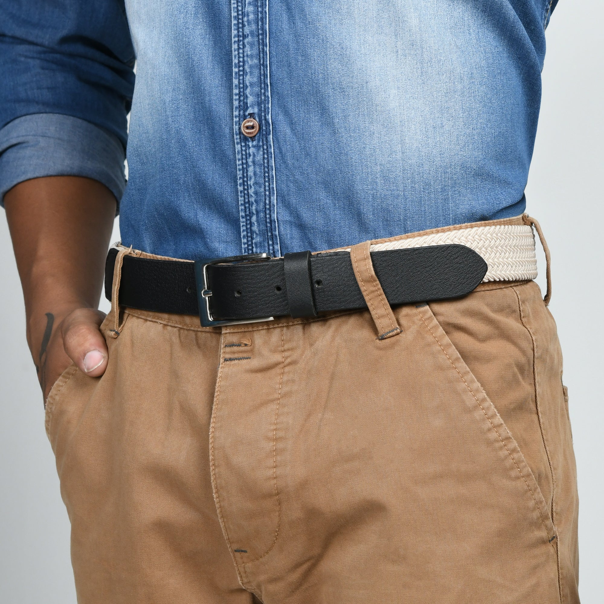 Person wearing a black belt with beige and blue clothing on a gray background