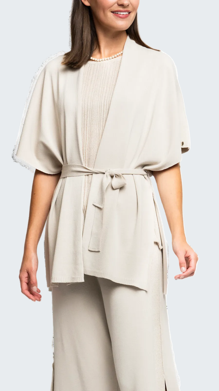 Woman wearing a beige outfit with a matching jacket and pants on a white background