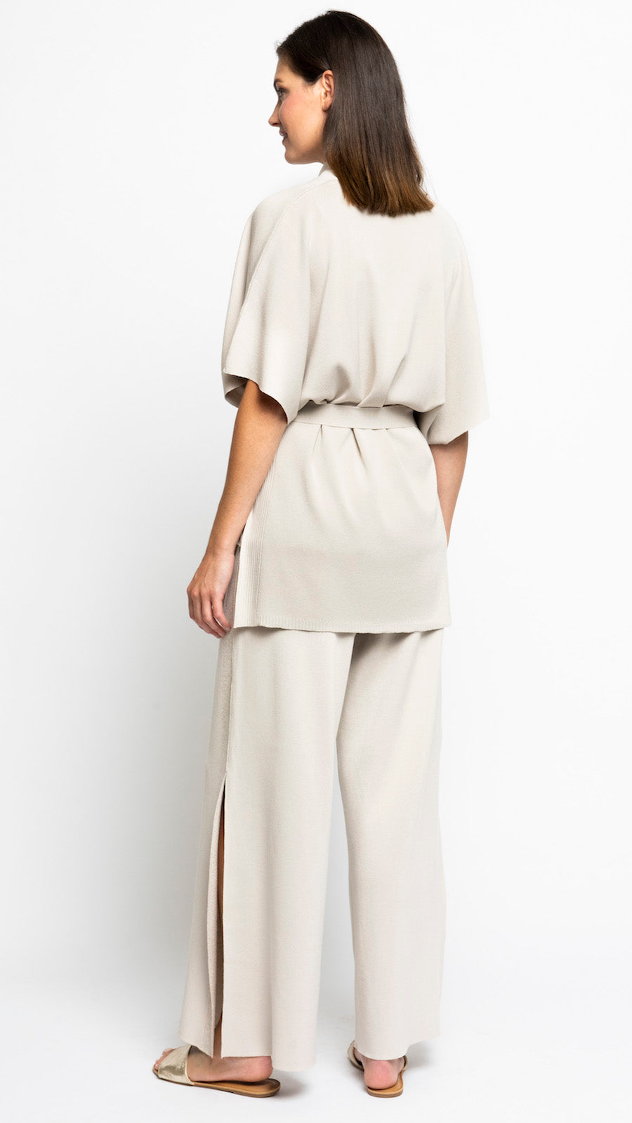 Woman wearing a beige outfit with wide-leg pants on a white background