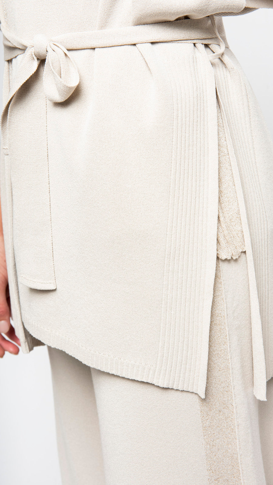 Close-up of a person wearing a light-colored outfit with a belt.