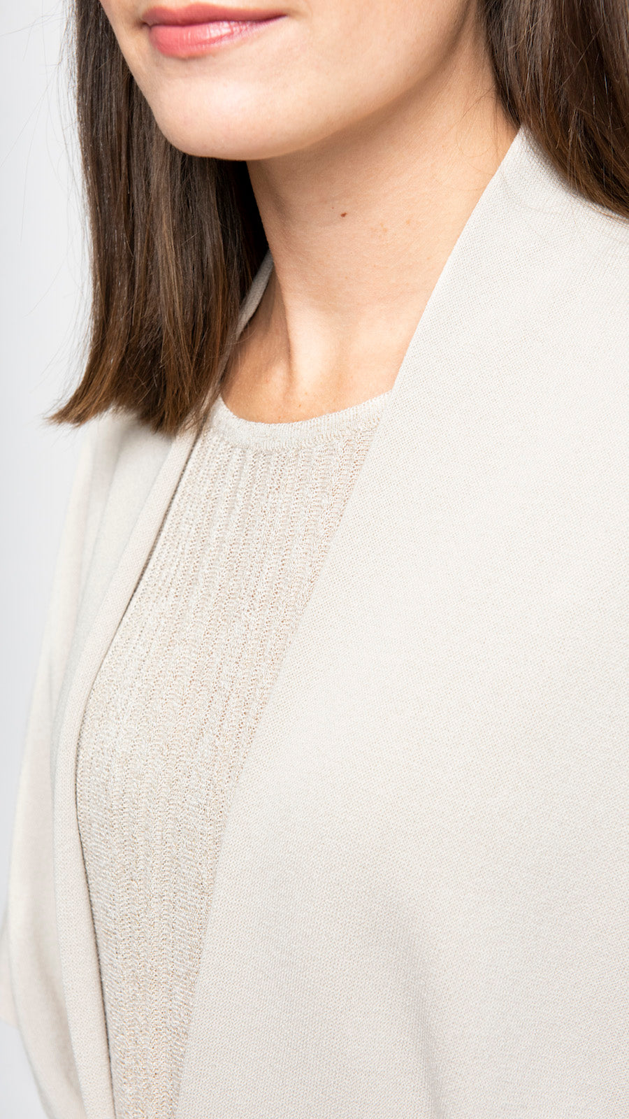 Close-up of a person wearing a light-colored outfit with a plain background