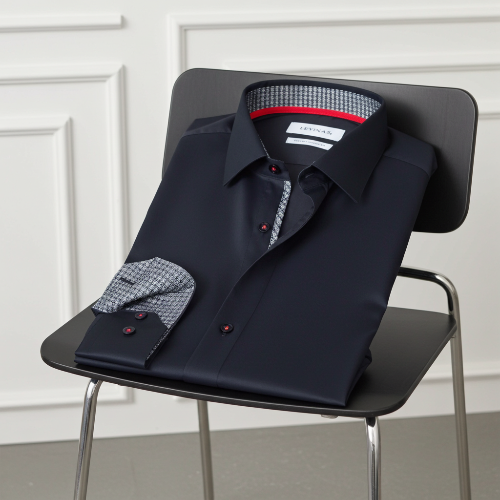 Dark blue dress shirt with patterned cuffs and collar on a black chair against a white paneled wall.