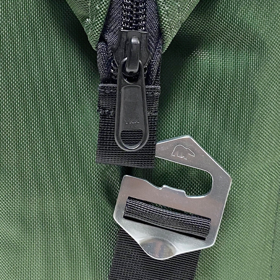 Close-up of a green bag with a black zipper and metal hook on a green background