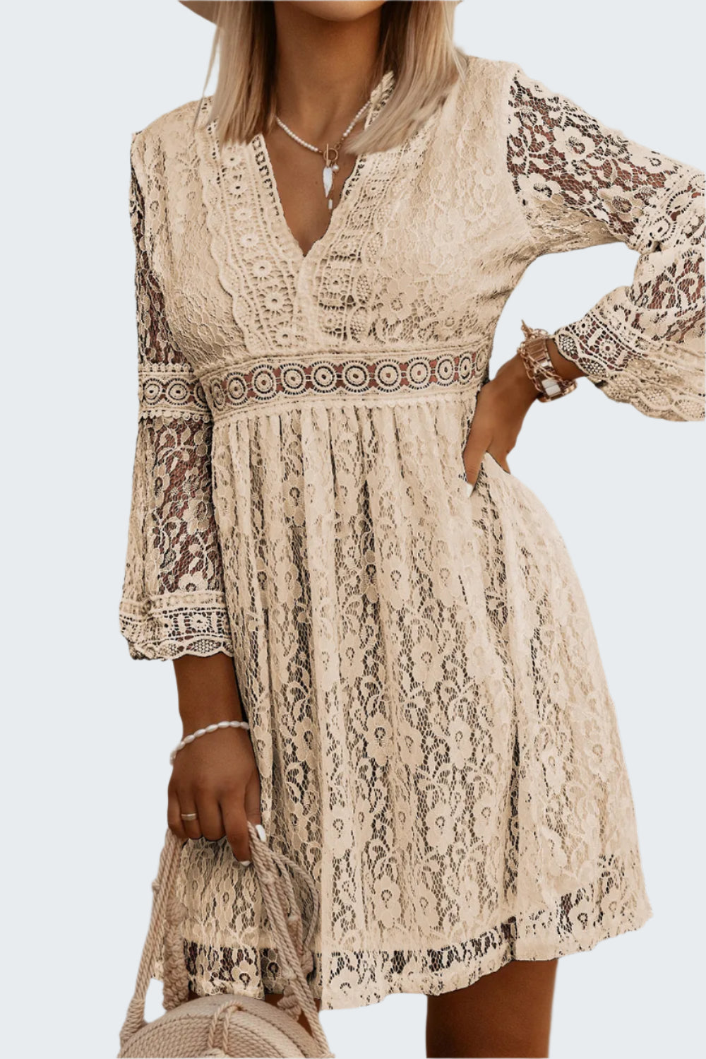 A woman wearing a beige lace v-neck three-quarter sleeve dress with floral patterns.