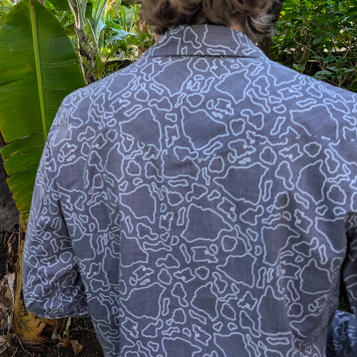 Person wearing a blue patterned shirt with a tropical background